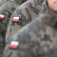 Żołnierze w mundurach moro z polskimi flagami na ramionach, przygotowujący się do rozliczenia delegacji zagranicznej.