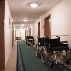 Korytarz z rzędami wózków inwalidzkich, sugerujący świadczenie rehabilitacyjne po ustaniu zatrudnienia.