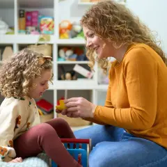 Mama z córką bawią się w pokoju pełnym zabawek. Czy urlop wychowawczy wlicza się do stażu pracy? To pytanie nurtuje wiele mam.
