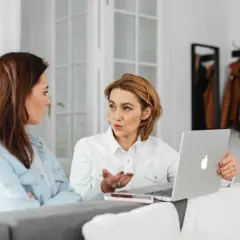 Dwie kobiety omawiają wynagrodzenie za urlop, analizując dane na laptopie.