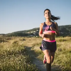 Kobieta biegnie przez łąkę. Zastanawia się nad kartą multisport cena, by mieć dostęp do wielu aktywności.