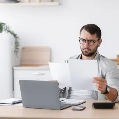 Mężczyzna w okularach analizuje dokumenty, zastanawiając się nad przywilejami dla osób z 3 grupą inwalidzką.