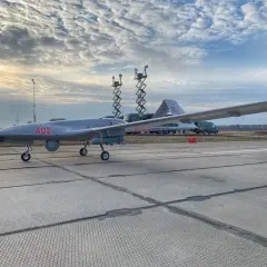 Szary dron Bayraktar TB-2 z numerem 402 na płycie lotniska, gotowy do akcji.