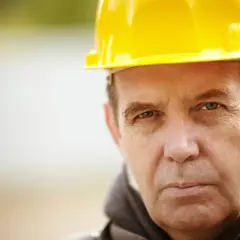 Mężczyzna w żółtym kasku, przygotowujący dokumentację ZUS wykaz stanowisk pracy w szczególnych warunkach.