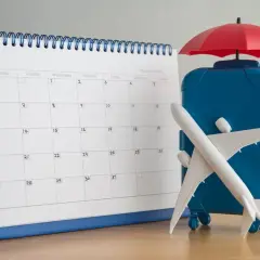 Kalendarz i walizka z samolotem sugerują planowanie urlopu po zmianie pracy.