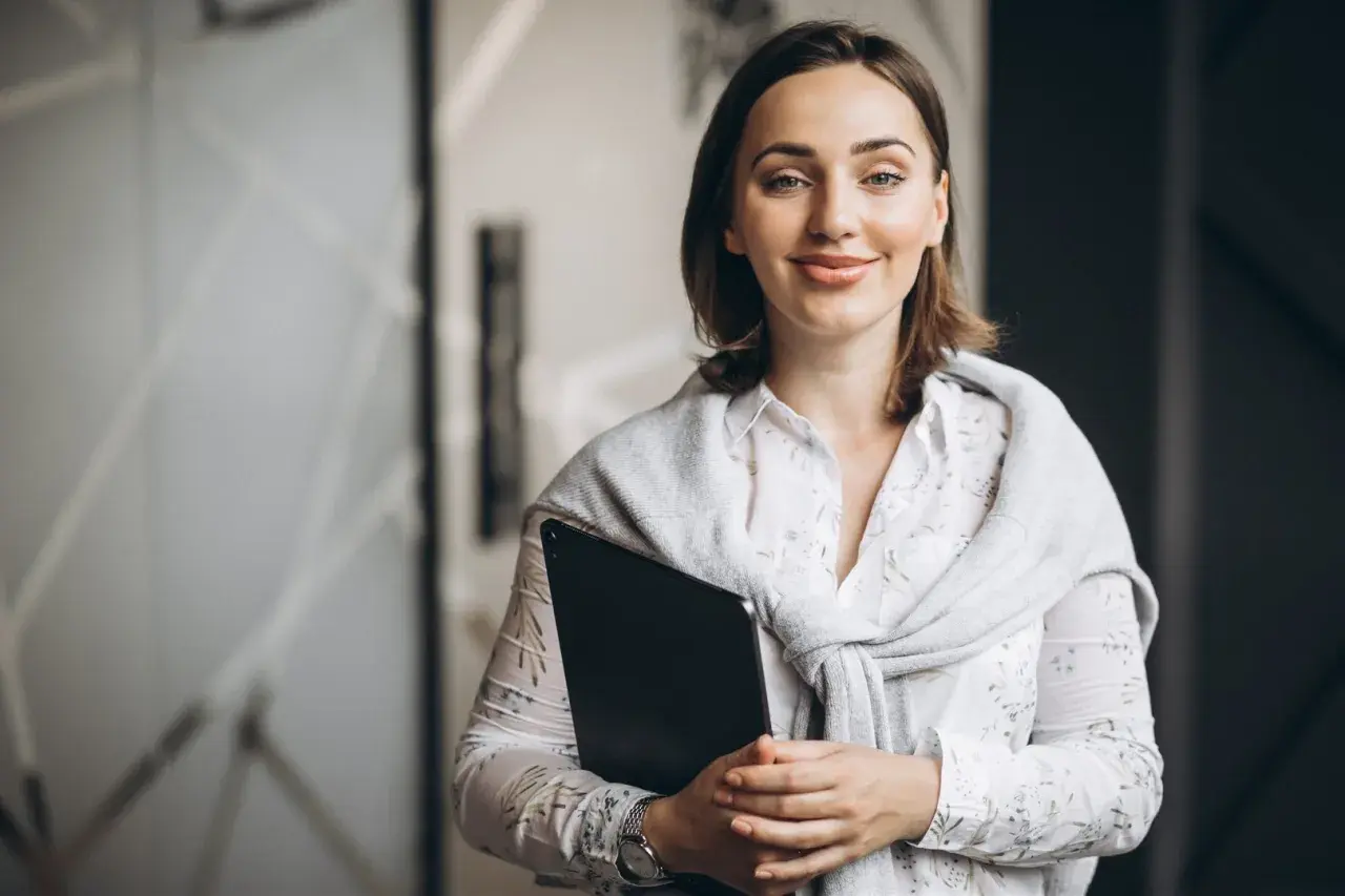 Uśmiechnięta nauczycielka z teczką, przygotowująca się do spełnienia wymagań na nauczyciela mianowanego po staremu.