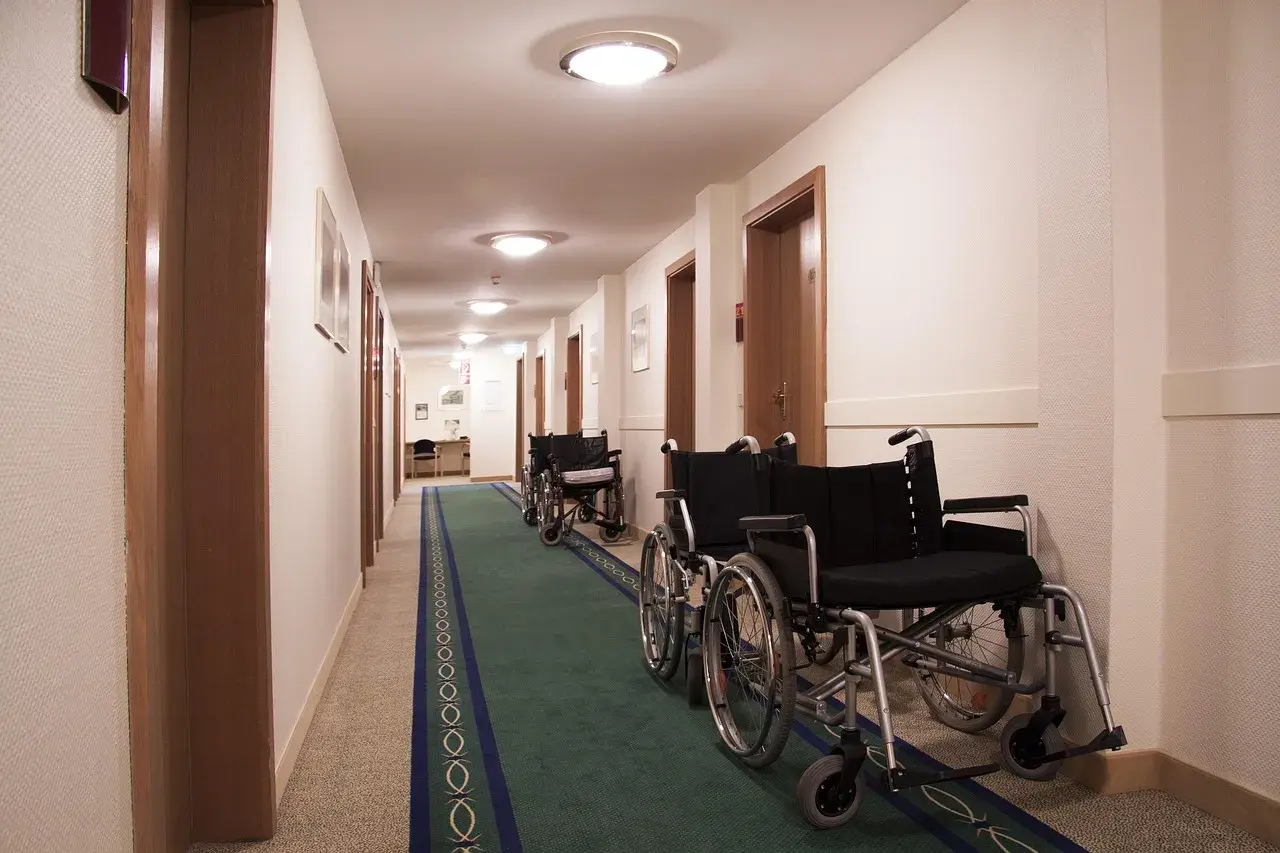 Korytarz z rzędami wózków inwalidzkich, sugerujący świadczenie rehabilitacyjne po ustaniu zatrudnienia.