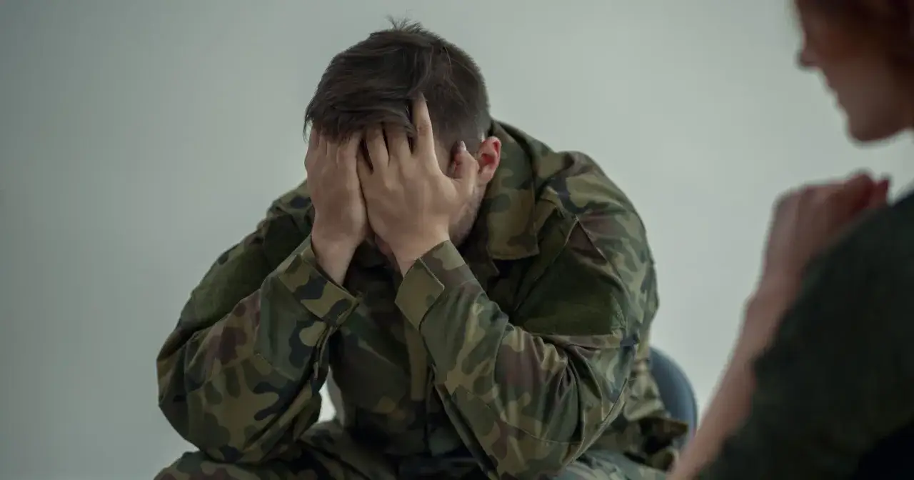 Żołnierz w mundurze, z rękami na twarzy, przechodzi trudne testy psychologiczne do wojska.