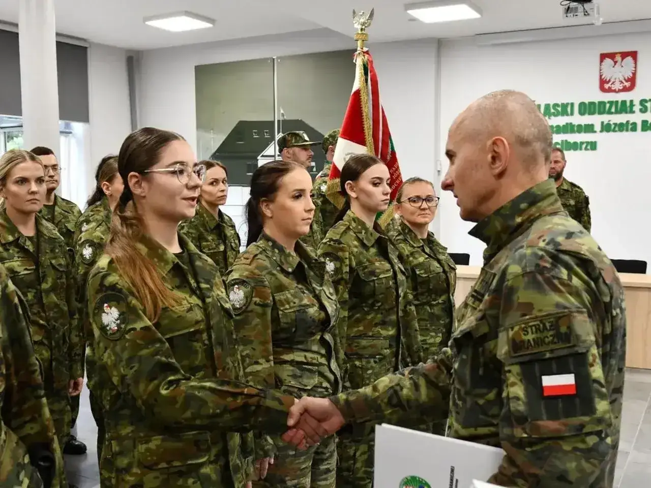 Strażnik graniczny wita nowych funkcjonariuszy. Uroczyste wręczenie odznaczeń i gratulacje dla młodych adeptów służby.