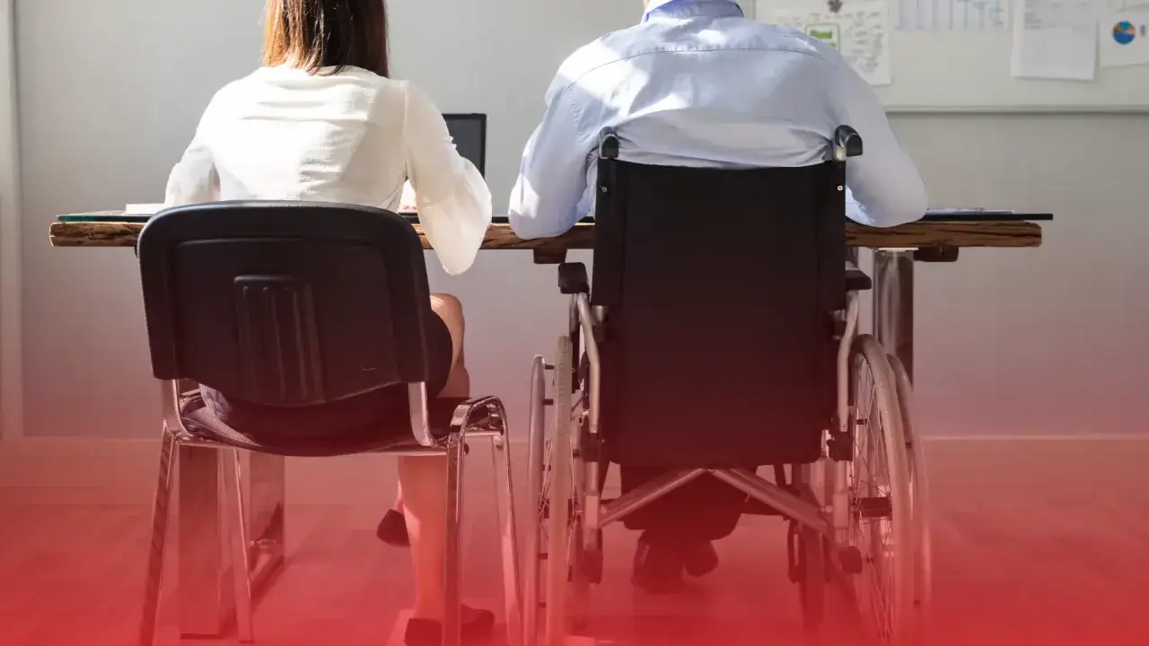 Osoba na wózku inwalidzkim i koleżanka przy biurku. Równość w pracy, 3 grupa inwalidzka przywileje.