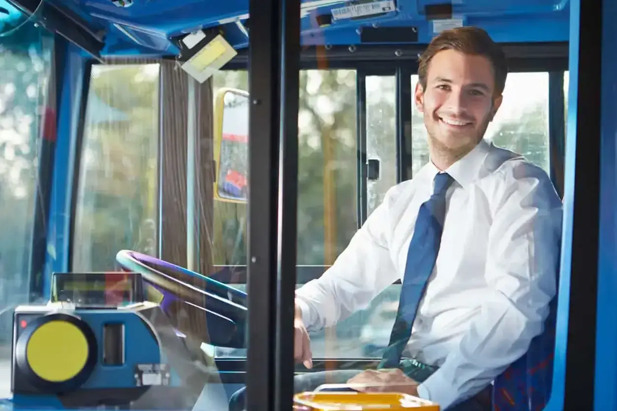 Uśmiechnięty kierowca autobusu w białej koszuli i krawacie. Zastanawiasz się, ile zarabia kierowca autobusu?