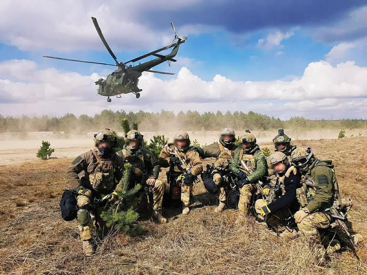 Agat wojsko w pełnym rynsztunku, z helikopterem w tle. Gotowi do akcji, w otoczeniu polnej drogi i lasu.