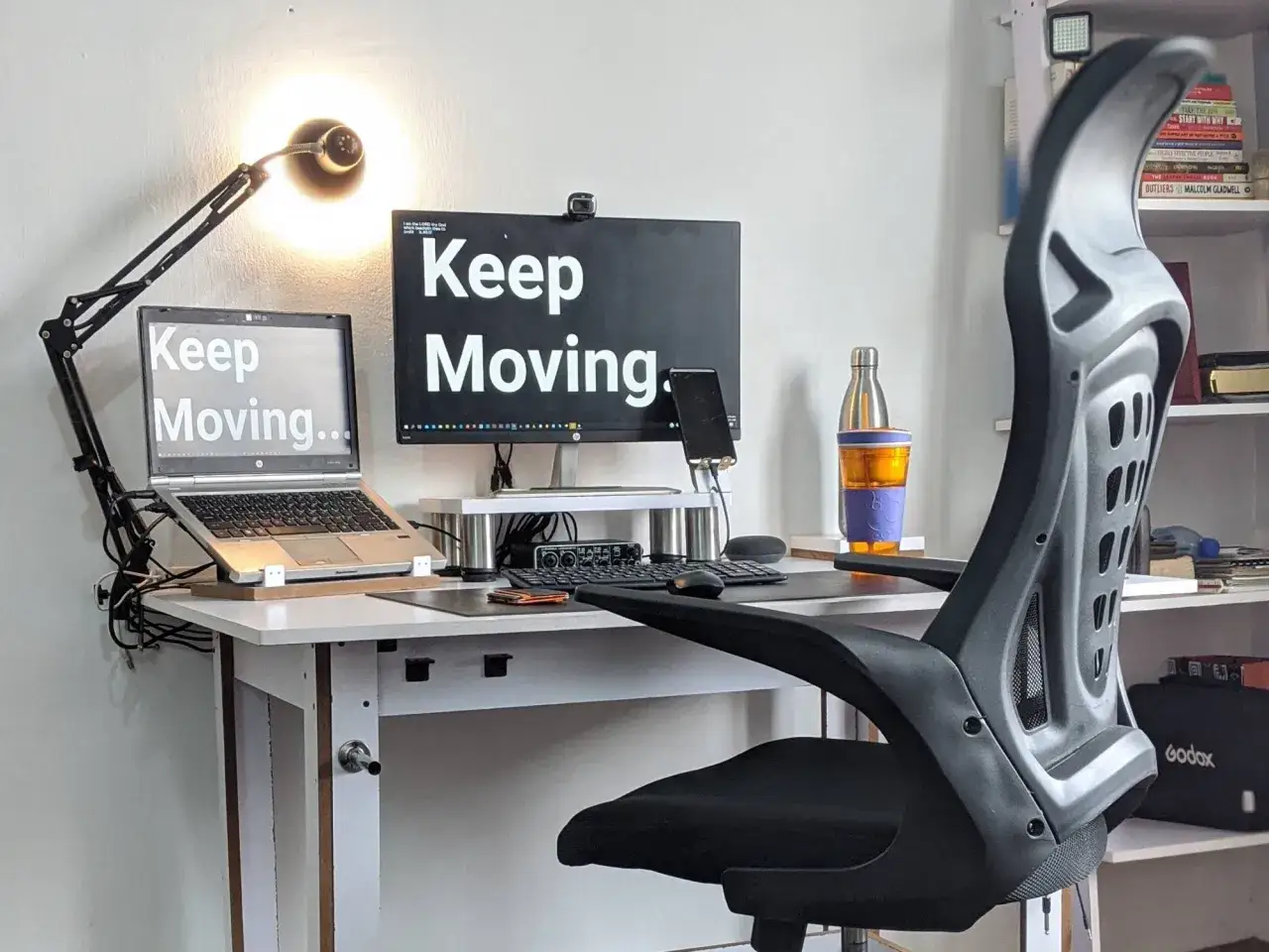 Ergonomia pracy: biurko z laptopem i monitorem, lampka, wygodne krzesło. Motywujące napisy