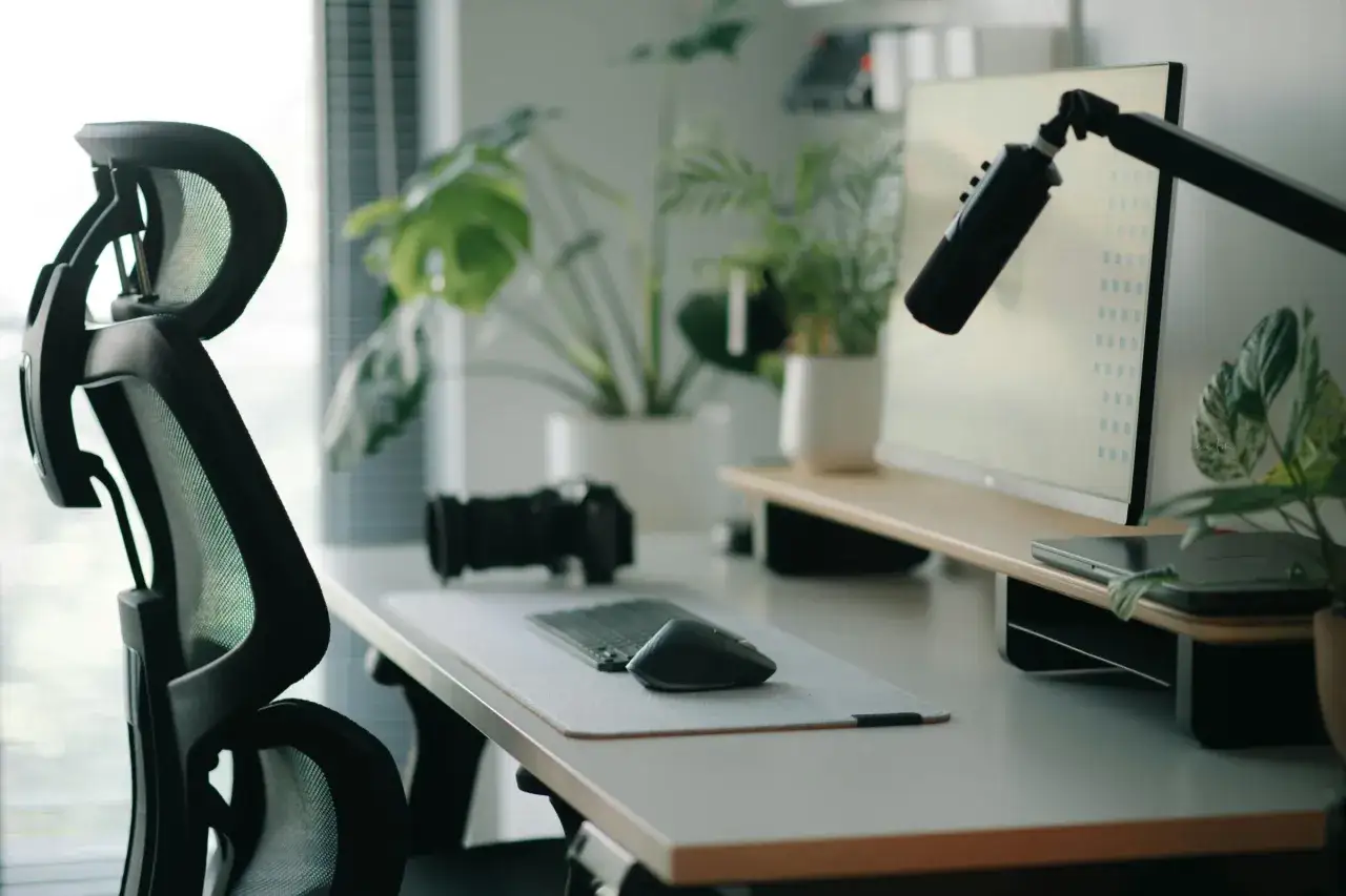 Ergonomia koncepcyjna w biurze: wygodne krzesło, monitor na podwyższeniu, mikrofon i rośliny tworzą idealne miejsce pracy.