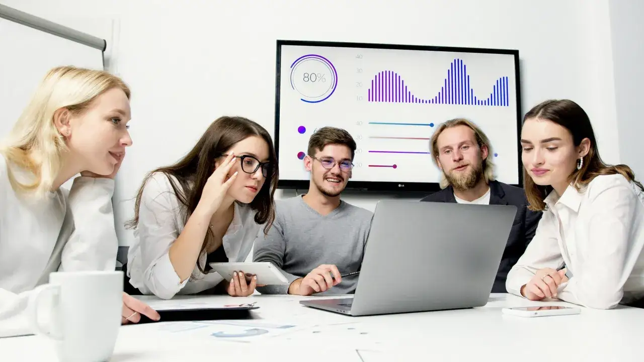 Młodzi millenialsi analizują wykresy na ekranie i laptopie.